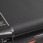 Close-up of black textured treadmill belt and frame showing motor housing and safety warning label