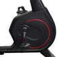 Black recumbent exercise bike with red accent circle and integrated display console, side view on white background