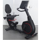 Black recumbent exercise bike with red accents, padded seat and backrest, digital display console, and stationary wheel on wh