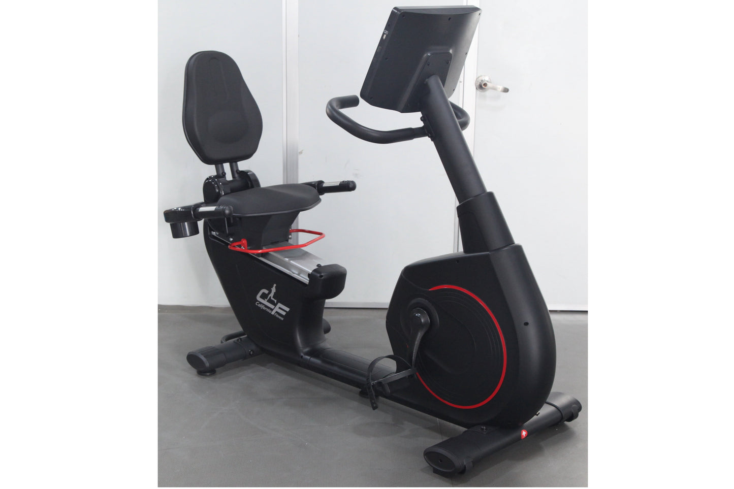 Black recumbent exercise bike with red accents, padded seat and backrest, digital display console, and stationary wheel on wh