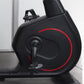 Black recumbent exercise bike with red circular accent design and digital display, side view on white background