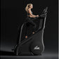 Woman in black sports bra and leggings using black California Fitness stair climber machine against dark background
