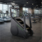 Black stair climber with digital display console, green accent stripe, and yellow step treads in modern gym setting