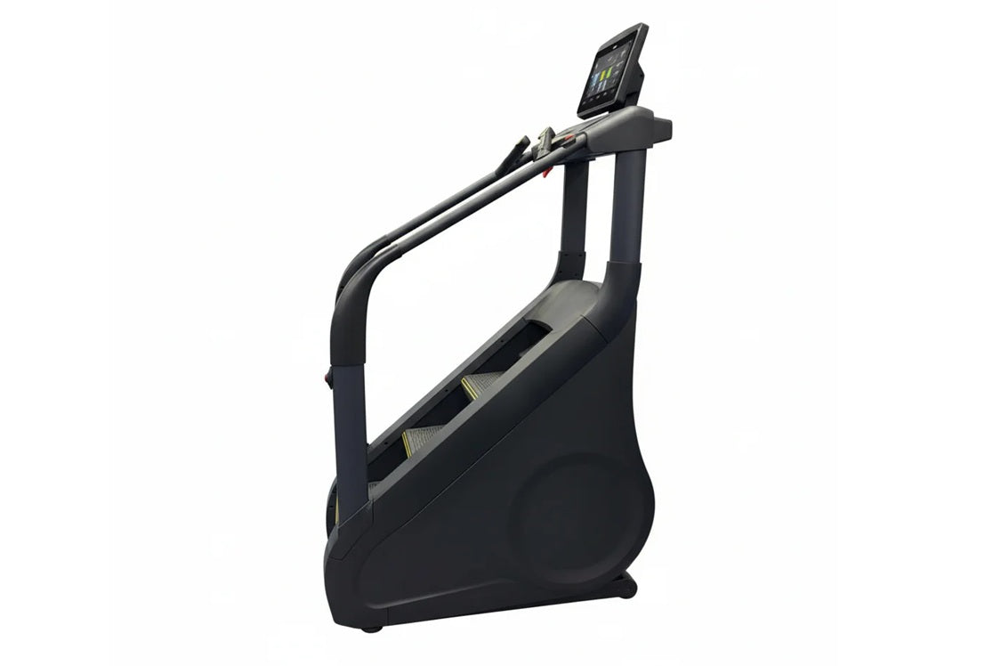 Black upright stair climber with digital display screen mounted on handlebar, pedal steps, and curved frame on white backgrou