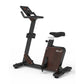 Black and brown upright exercise bike with digital display console, padded seat, and foot pedals on white background