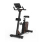 Black and brown upright exercise bike with digital display console, padded seat, handlebars, and foot pedals on white backgro