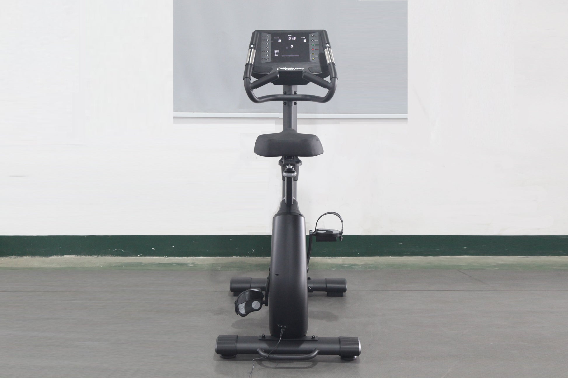 Black upright exercise bike with digital display console, padded seat, handlebars, and pedals on stable base, front view