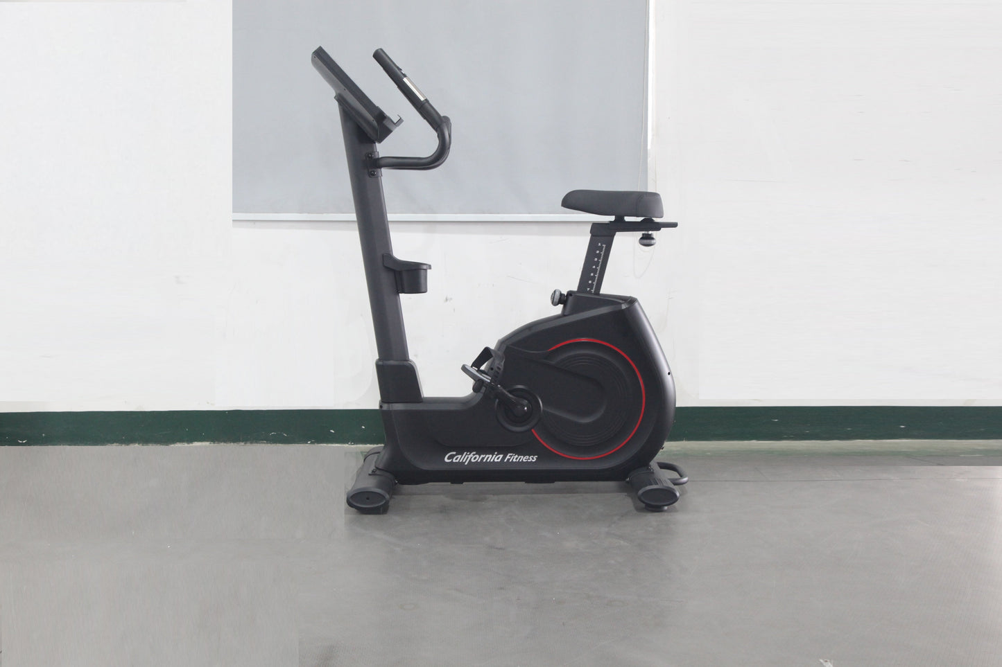 California Fitness U8 upright exercise bike with black frame, red wheel accents, padded seat, and handlebars on gray floor