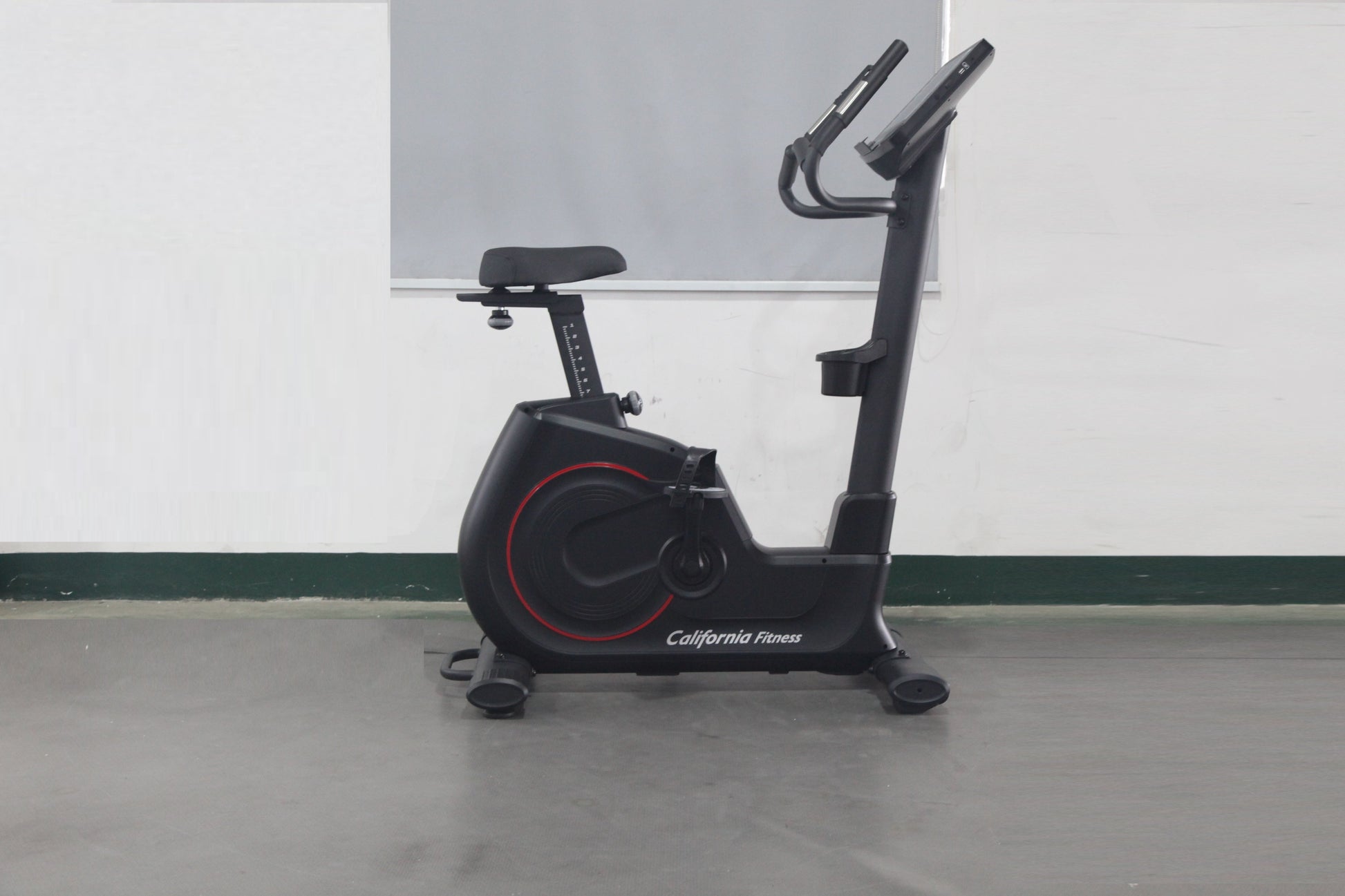 California Fitness U8 black upright exercise bike with red accent wheel and digital display on gray background