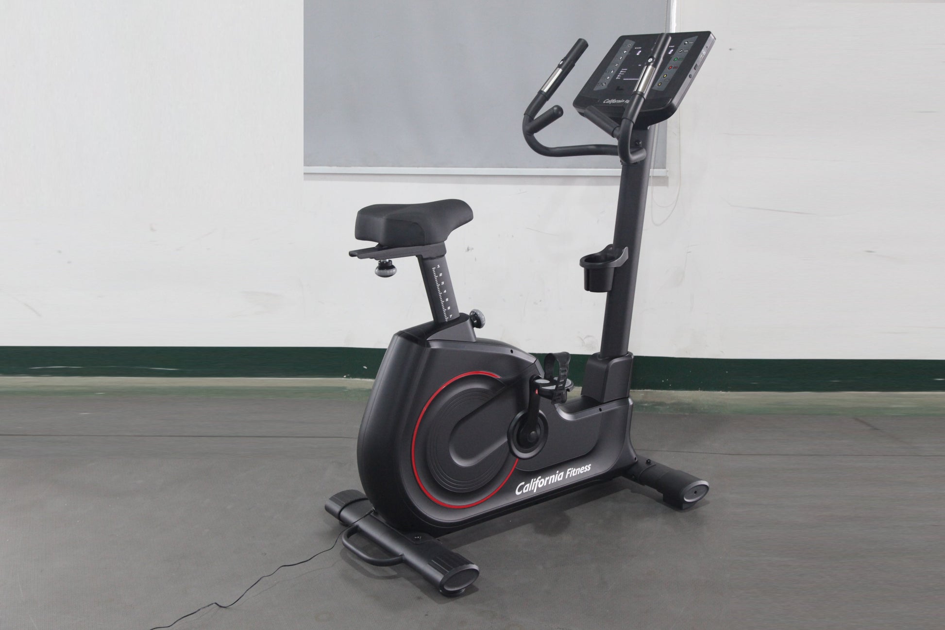 California Fitness U8 black upright exercise bike with red accents, digital display console, and padded seat on gray floor