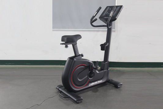 California Fitness U8 black upright exercise bike with red accents, digital display console, and padded seat on gray floor