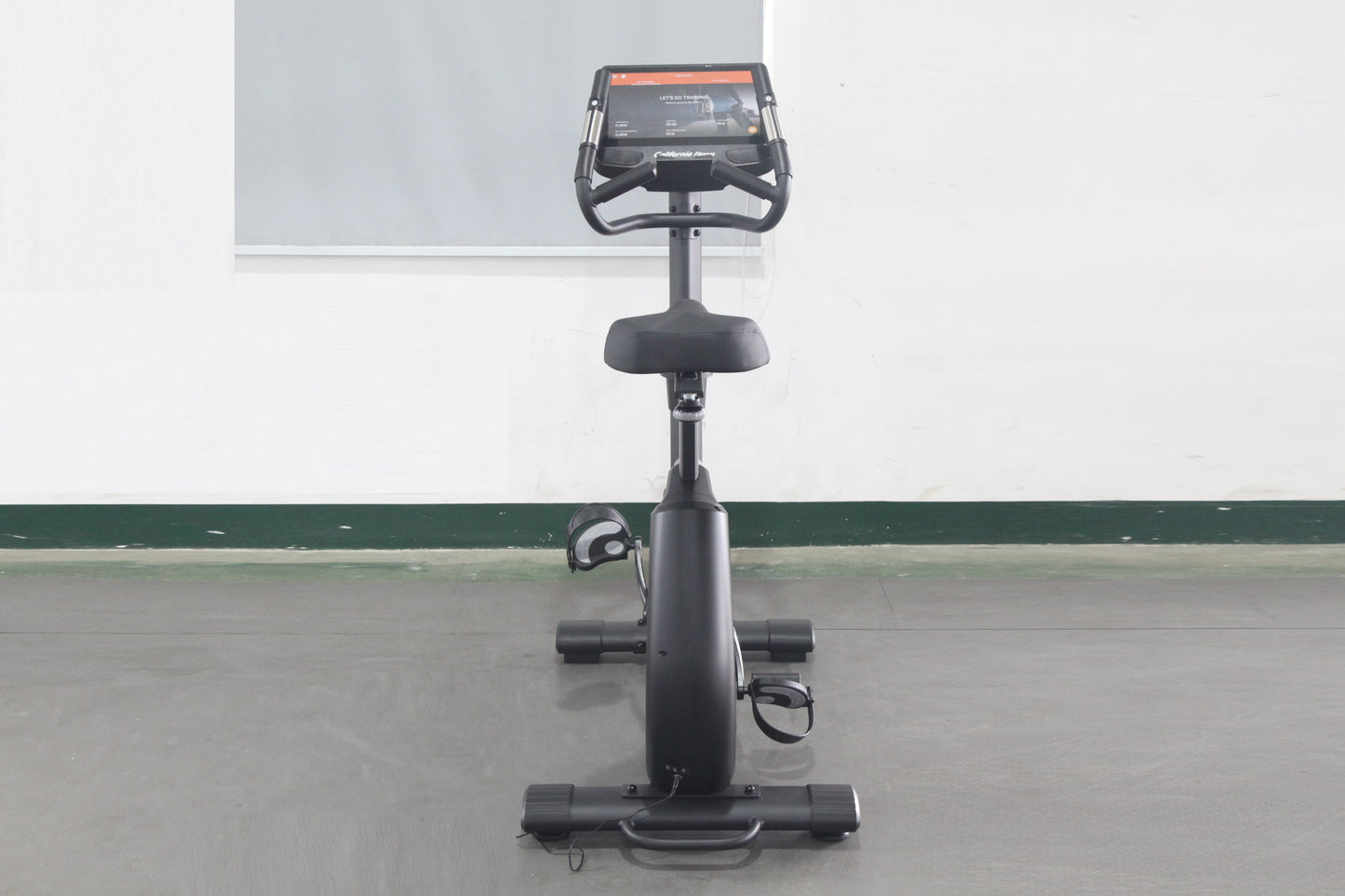 California Fitness U8 upright exercise bike with black frame, padded seat, handlebar console display, and foot pedals on whit