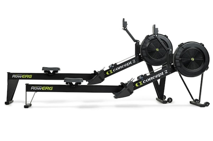 Black Concept2 RowErg indoor rowing machine with dual black resistance fans, extended arm, and stabilizing legs on white back