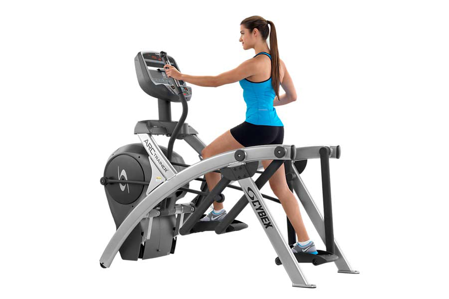 Woman in blue tank top using Cybex 525AT Total Body Arc Trainer elliptical with digital console on white background