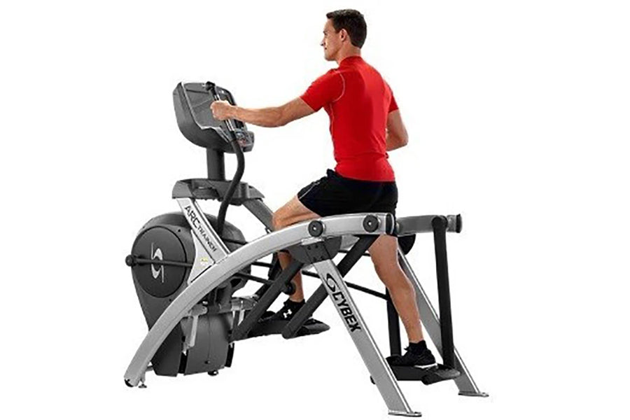 Man in red shirt and black shorts using stationary arc trainer with digital console on white background