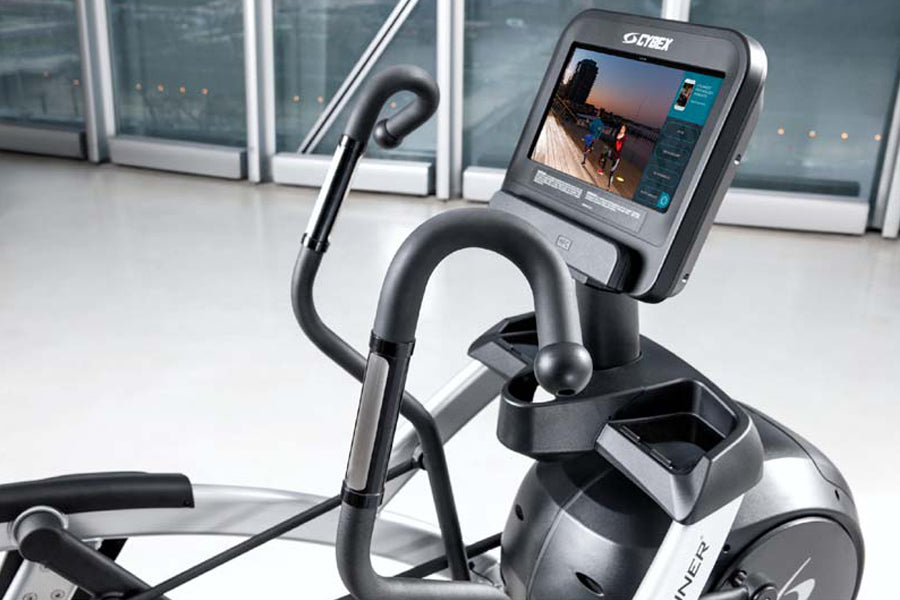 Black and gray Cybex R Series arc trainer with digital touchscreen display showing workout metrics, curved handlebars, and pe