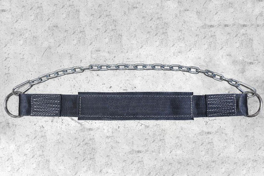 Metal chain dip belt with black nylon padding and webbing straps, flat lay on concrete background