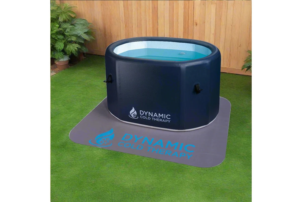 Dynamic Cold Therapy black inflatable oval cold plunge pool with turquoise water, shown on gray mat in outdoor garden setting