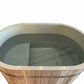 Oval cold plunge barrel with natural cedar wood exterior and pale green interior, featuring metal rim and drainage system, on
