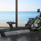 Black and neon yellow magnetic rowing machine with digital display, positioned indoors overlooking ocean view