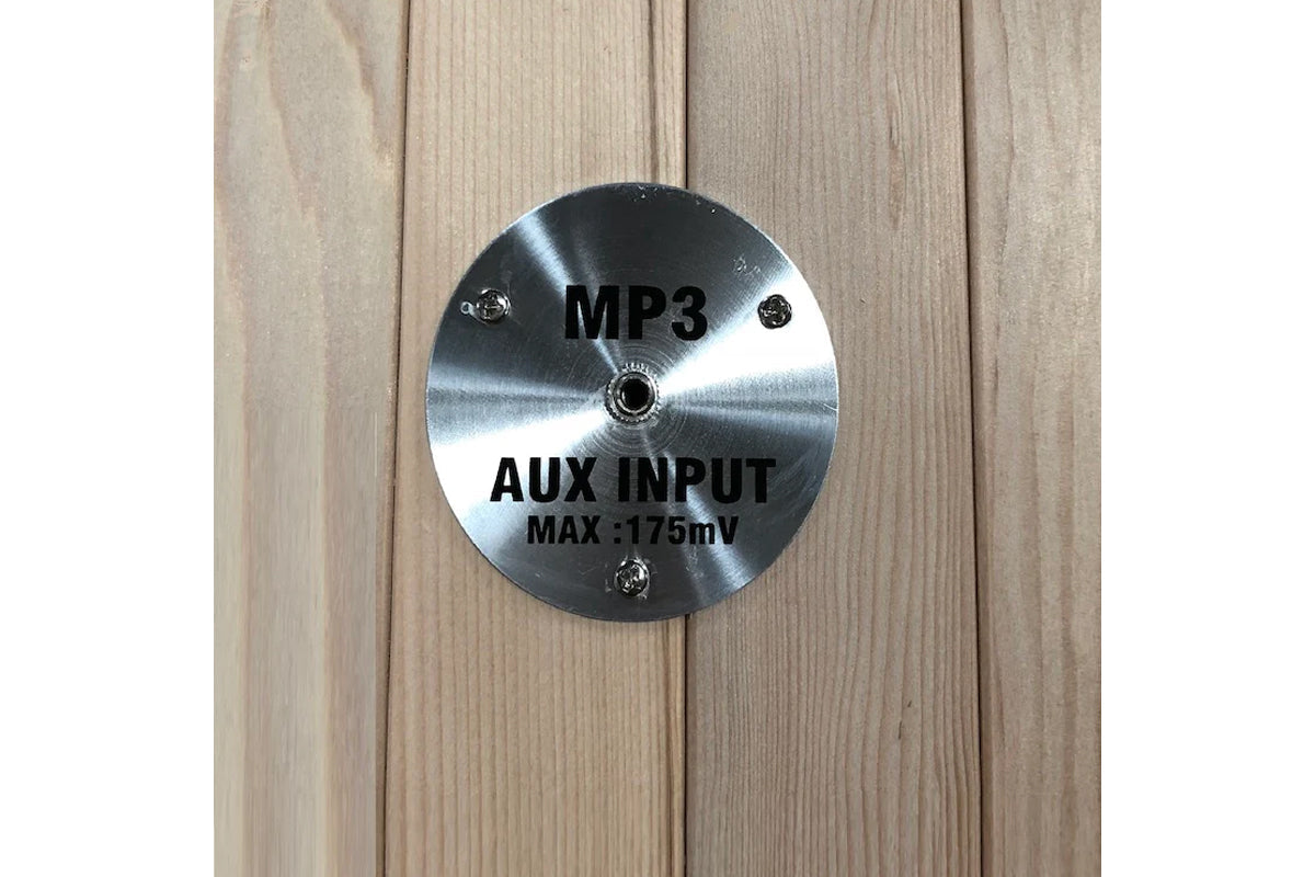 Brushed metal circular panel with MP3 and AUX input labels on wood sauna interior