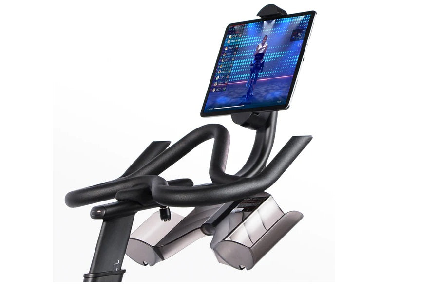 Black and gray stationary exercise bike with curved handlebars, tablet holder displaying fitness app on white background
