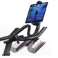Black and gray stationary exercise bike with curved handlebars, tablet holder displaying fitness app on white background
