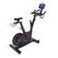 Black and red upright stationary exercise bike with tablet holder, handlebar grips, and weighted flywheel on white background