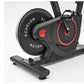Black and red stationary exercise bike with large flywheel, pedals, and handlebars on white background