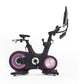 Black stationary exercise bike with pink illuminated wheels, digital console, and adjustable tablet holder on white backgroun