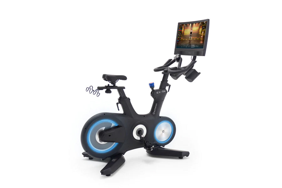 Black stationary exercise bike with blue accent wheels and handlebar monitor displaying workout video on white background