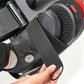 Gaming headset with black and gray ear cups, perforated padding, and red accents, held in hand against white background