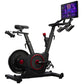 Black and red stationary exercise bike with tablet holder displaying workout screen, on white background
