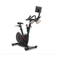 Black upright exercise bike with red accents, digital display mounted on adjustable arm, handlebars with controls, pedals, an