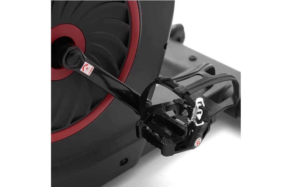 Black and red stationary exercise bike with pedal and adjustable seat, close-up detail view
