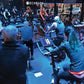 Group fitness class with multiple participants on black and red stationary bikes in Echelon studio with instructor leading wo