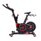 Black and red stationary exercise bike with curved handlebars, digital display, and weighted flywheel, on white background