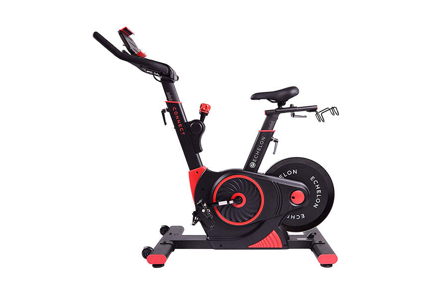 Black and red stationary exercise bike with curved handlebars, digital display, and weighted flywheel, on white background