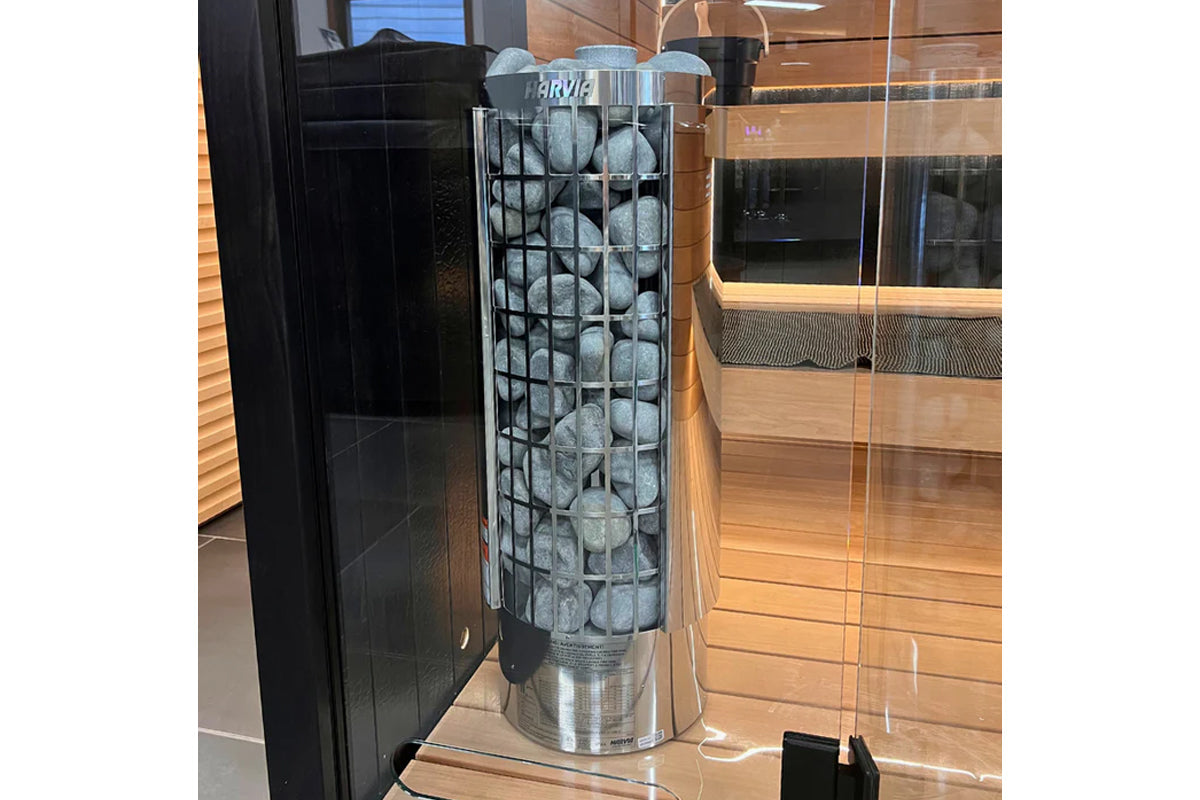 Harvia Cilindro electric sauna heater with black metal cage filled with gray stones, stainless steel base, displayed in showr