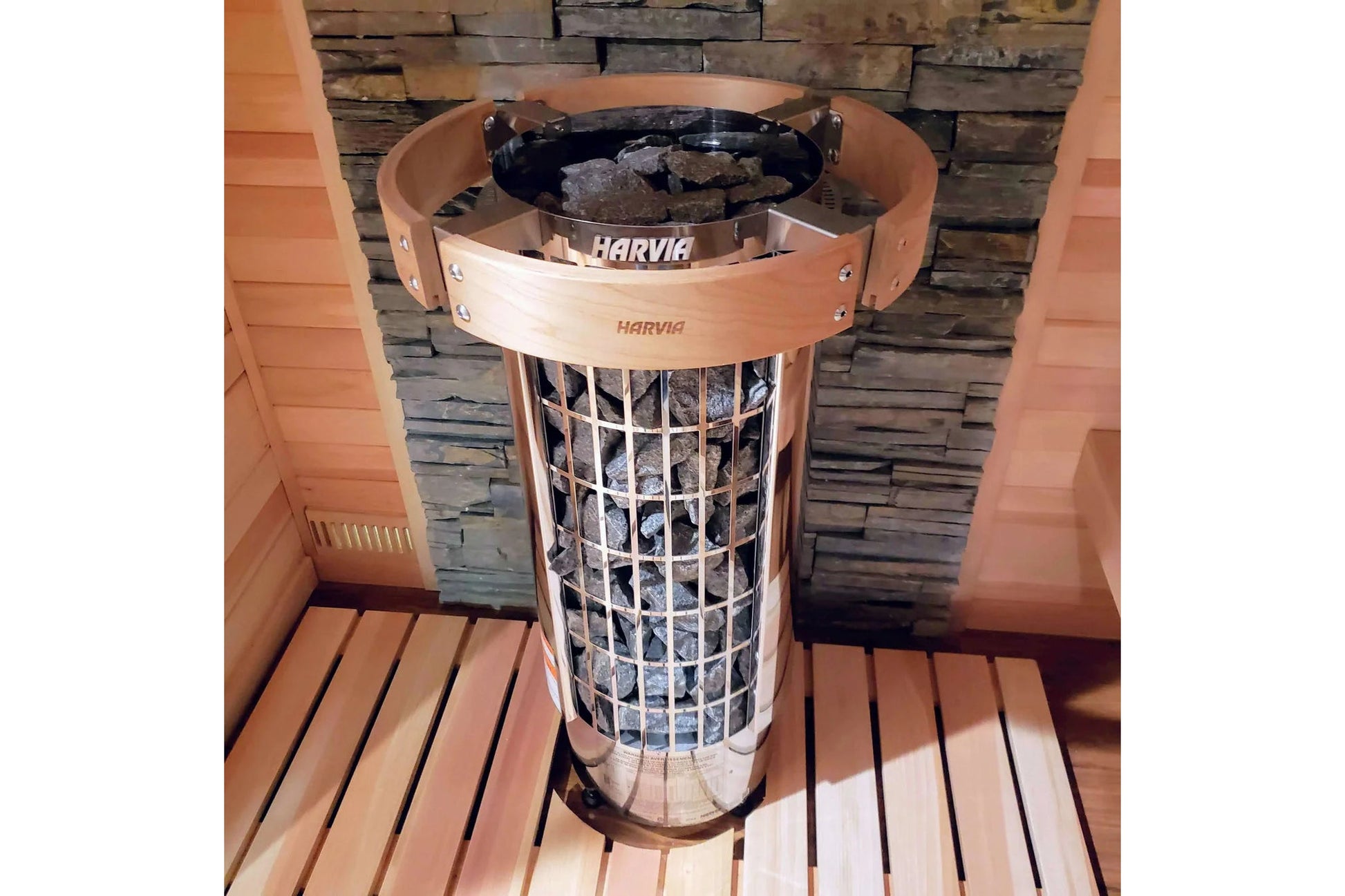 Harvia Cilindro electric sauna heater with black metal basket and light wood band, installed in sauna room with wooden walls 