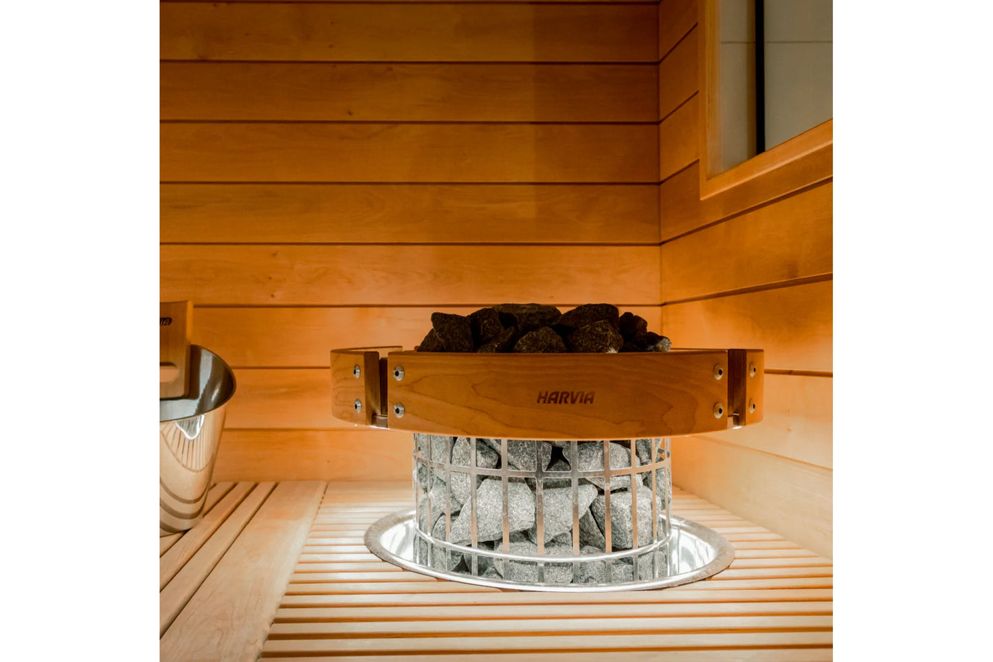 Harvia Cilindro electric sauna heater with wooden rim and metal basket filled with stones, positioned in wooden sauna interio