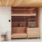 Modern cedar sauna interior with glass door, wooden benches, built-in heater with window, and stainless steel bucket with sto