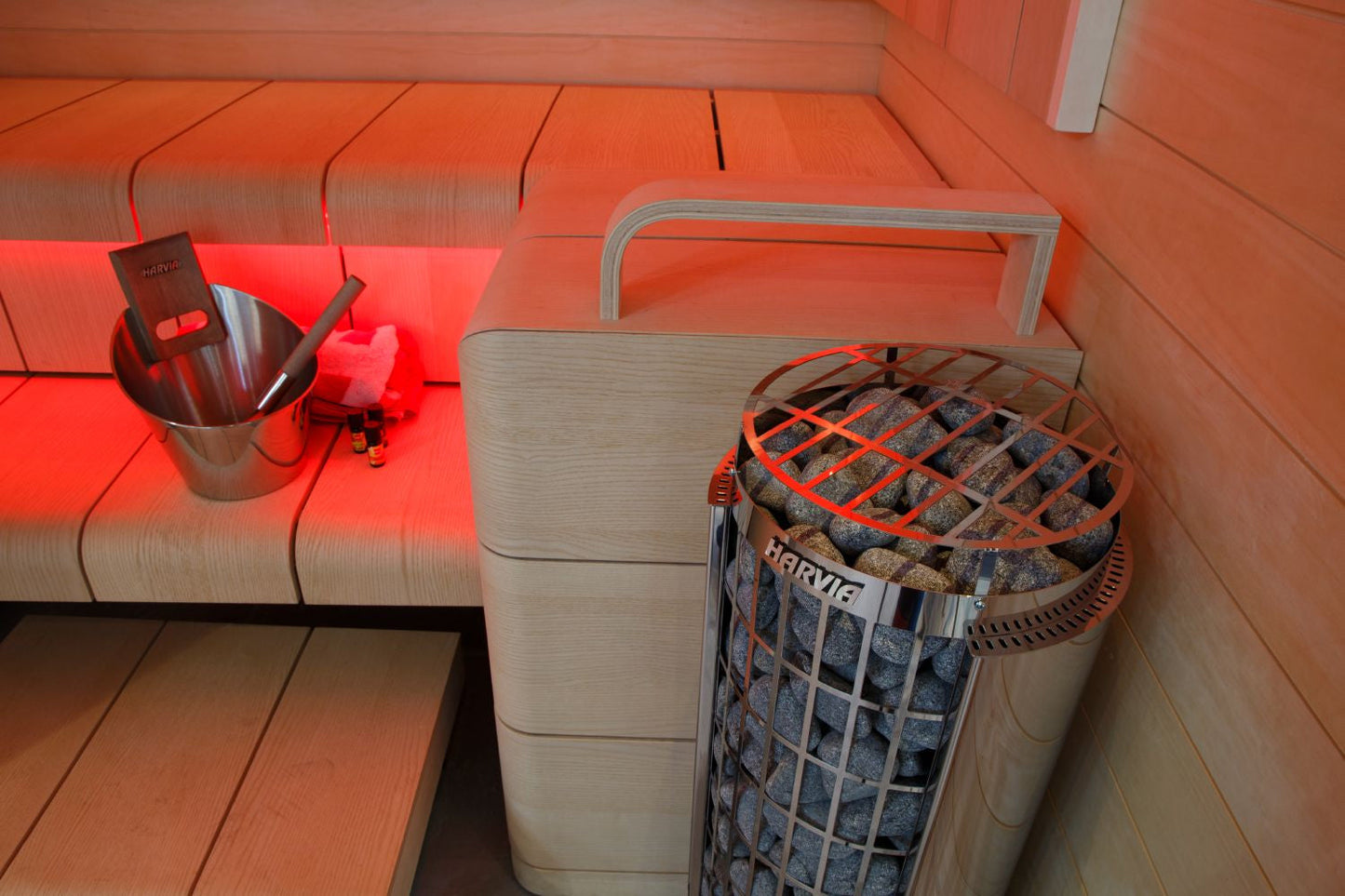 Harvia Cilindro electric sauna heater with built-in dial controls, stainless steel basket filled with grey stones, orange met