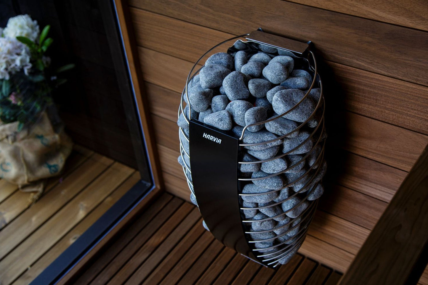 Harvia Spirit electric sauna heater with gray stones in metal basket on wooden deck