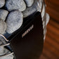 Harvia Spirit sauna heater with gray stones in metal basket, black control panel visible, on wooden background