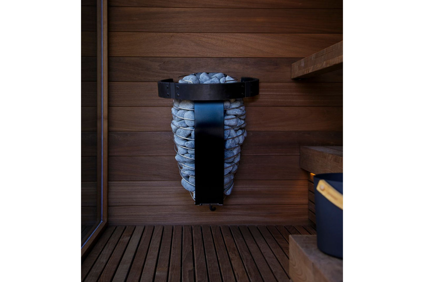 Harvia Spirit electric sauna heater with black metal top and blue stones, mounted on wooden sauna wall