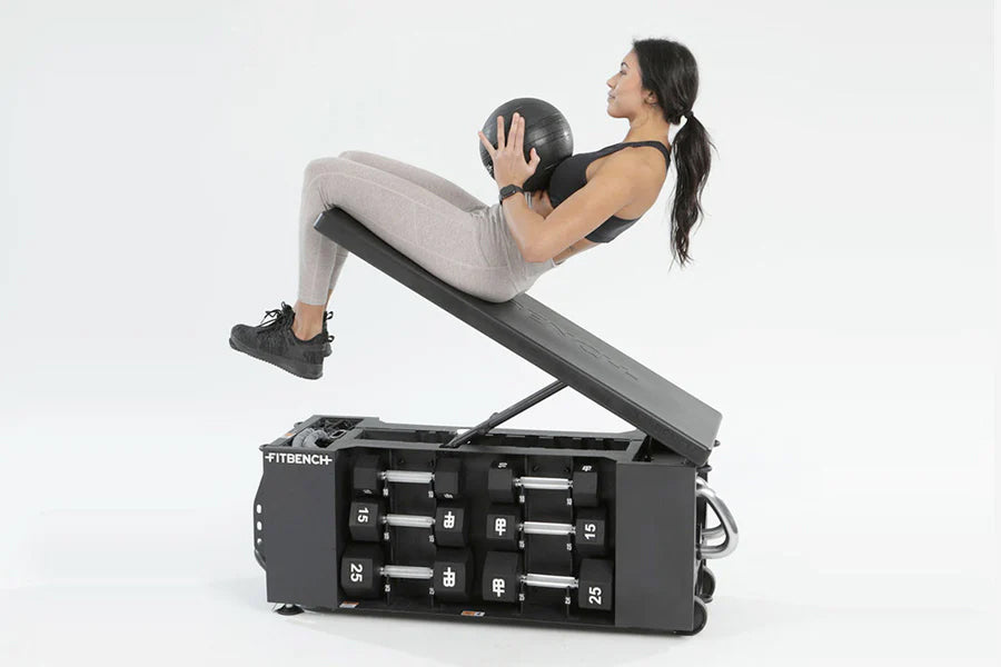 Woman performing medicine ball exercise on black FITBENCH ONE adjustable weight bench against white background