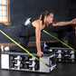 Two people performing plank exercises on FITBENCH STUDIO weight bench with neon yellow straps in gym setting