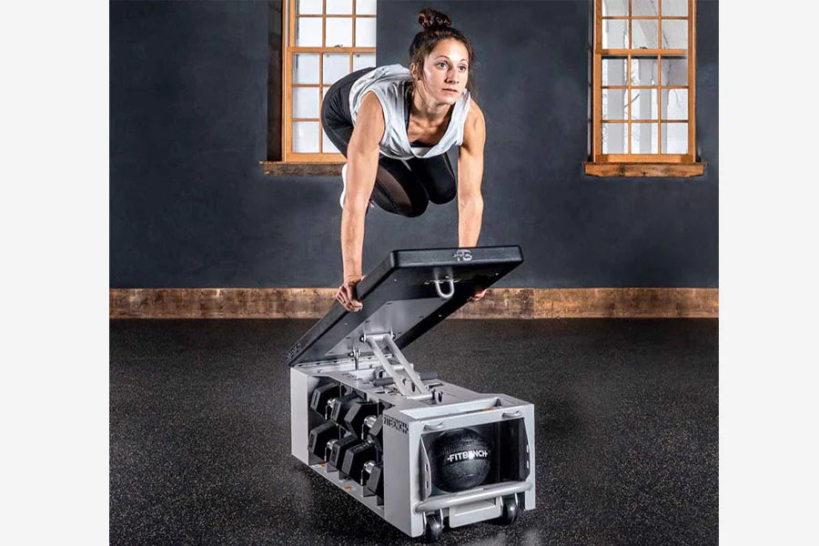 Woman in white tank and black pants using white and black weight bench in industrial gym setting