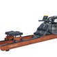 Apollo Pro rowing machine with wood-grain finish, digital display, and dual foot pedals on white background